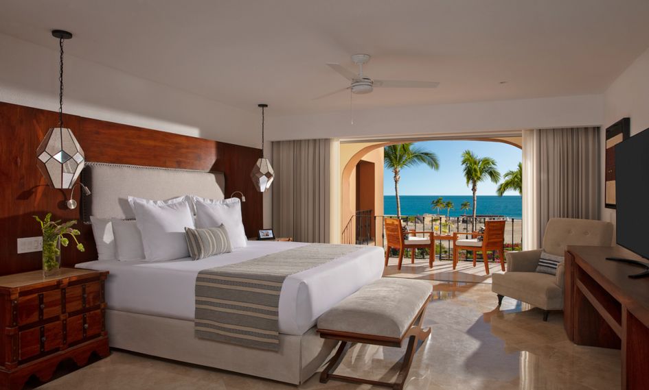 the Zoetry Casa del Mar Los Cabos room with a king bed and patio. The pation has two chairs looking out into the beach.