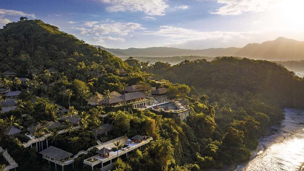 Aerial view of Amankila in Indonesia. The hotel is atop a lush mountain surrounded by the forest and overlooking the beach. 