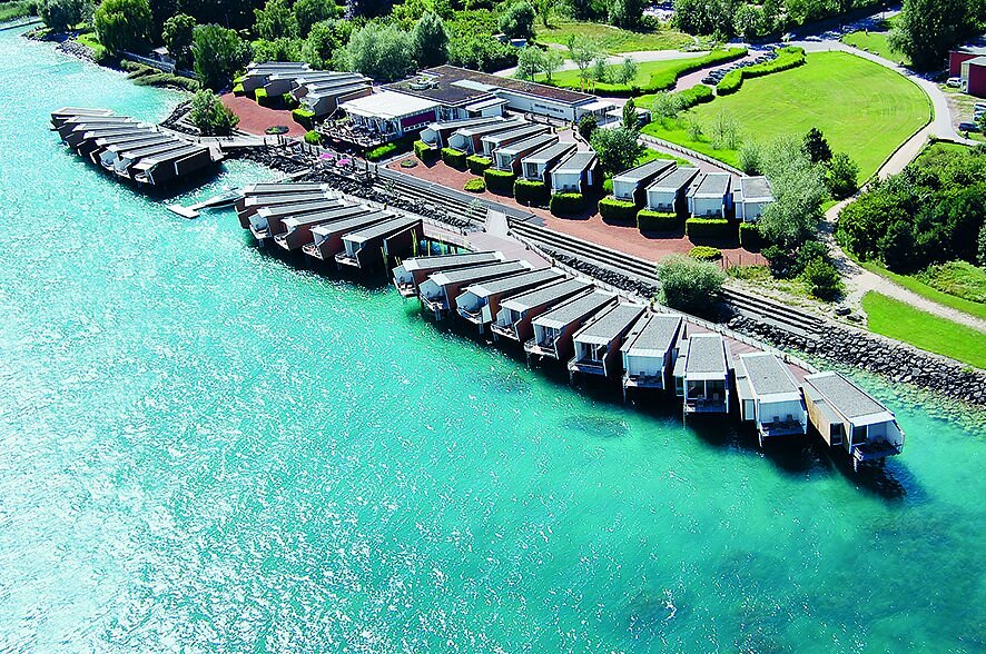 Aerial view of Hotel Palafitte. It's separate villas on stilts over the water overlooking the ocean with a large space of greenery behind the villas. 