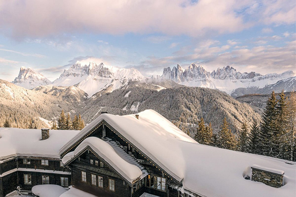 FORESTIS Dolomites covered in snow, surrounded by mountains and trees. 