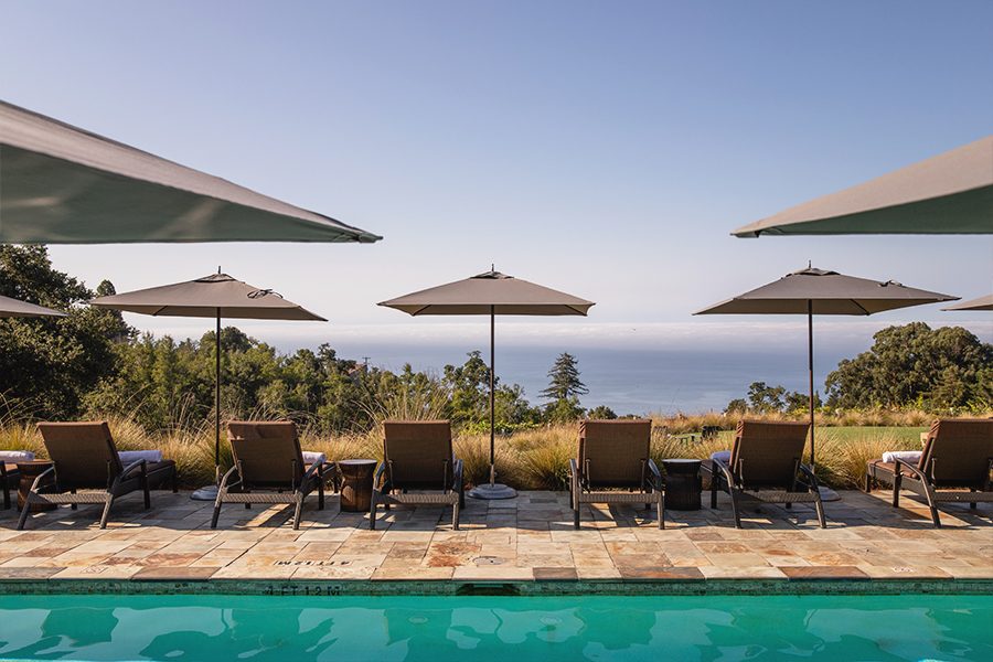 Partial view of a pool, pool chairs looking over the ocean horizon