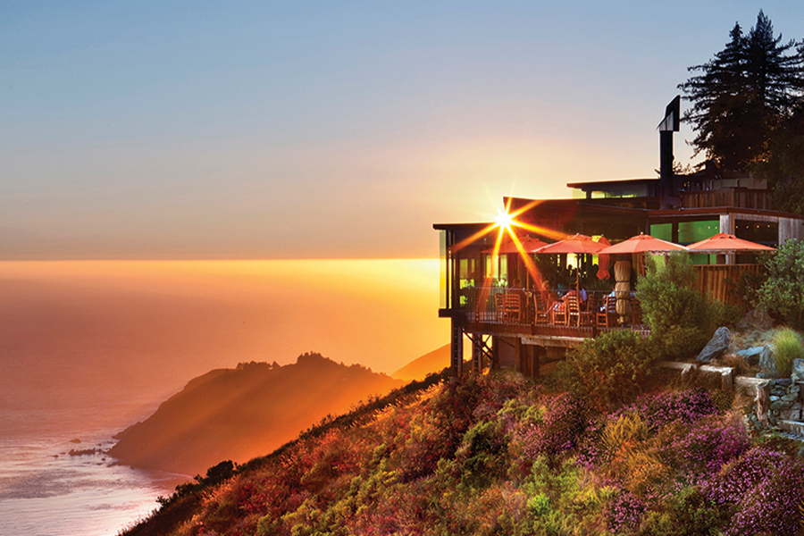 Overhead shot of Sierra Mar at Post Ranch Inn during sunset. The restaurant located on a hill overlooks teh ocean and rocky terrain. 