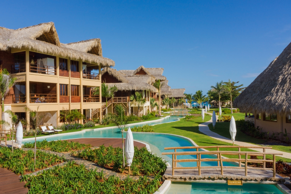 New building at Zoetry Agua Punta Cana overlooking grass and lagoon. 